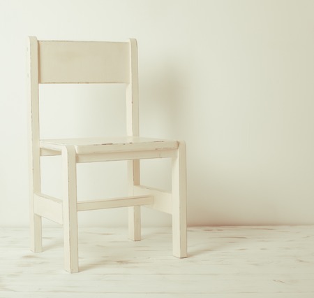 Single white rustic chair standing in an empty room on light wooden parquet floor.の写真素材