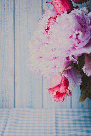 A fresh bouquet of pink peonies and tulips on a blue wooden backgroundの写真素材