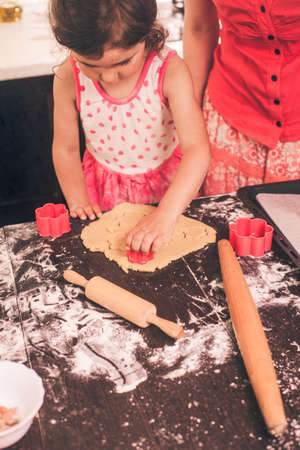 Little cute girl stretching the dough in the kitchenの写真素材