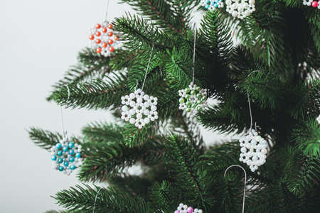 Snowflakes handmade beaded hanging on Christmas tree branches. Close-upの写真素材