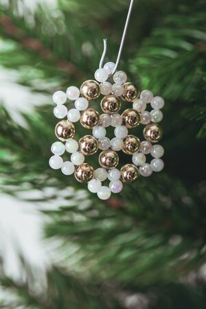 Snowflakes handmade beaded hanging on Christmas tree branches. Close-upの写真素材