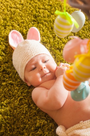 Three months baby lying and play with  Easter eggs mobile
