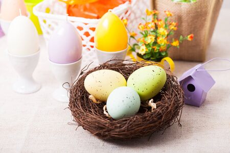 Easter decorations - egg candles, nest and flowers on the table