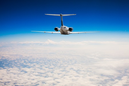 Rear view of a airplane that is flying high above the clouds