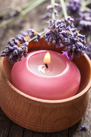 Sprig of fragrant lavender alongside a burning aromatic candleの写真素材