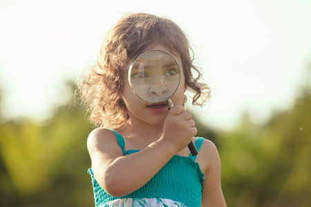 Kid plays with magnifying glass in the gardenの写真素材