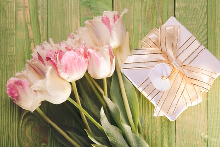 Pink tulips and gift box on a green wooden tableの写真素材