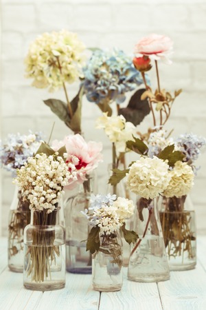 Flowers in bottles over white wall, vintage styledの写真素材