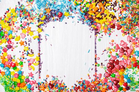 Various color sprinkles scattered on white wooden tableの写真素材