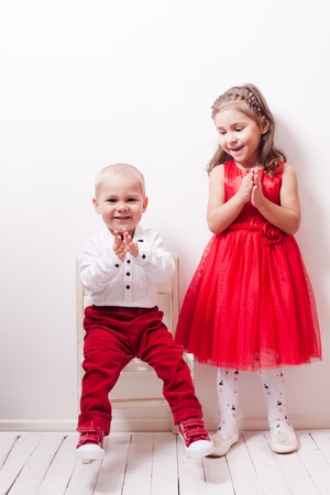 Little boy in red pants and a girl in a red dress posing for photos in harmonyの写真素材