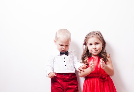 Little boy in red pants and a girl in a red dress posing for photos in harmonyの写真素材