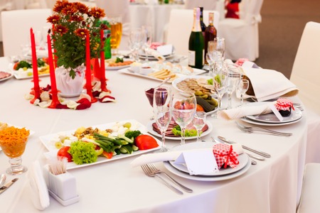 Table set for a wedding reception in white and red colors with gift on a plateの写真素材