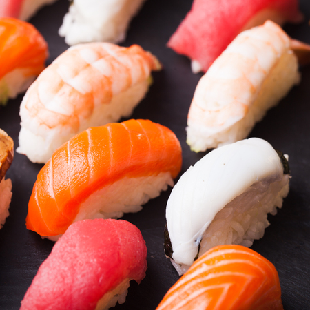 Close-up of set of four sushi with salmon, tuna, scallop and shrimp on a black backgroundの写真素材