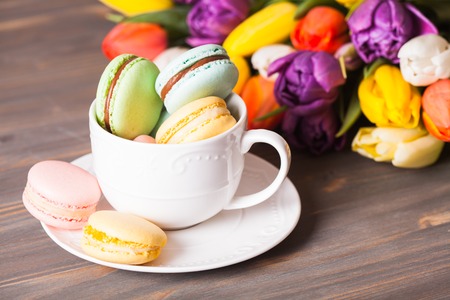 Color macaroons in a cup and flowers on the backgroundの写真素材