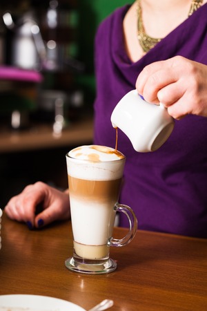 Barista is pouring coffee in milk - preparing coffe latteの写真素材