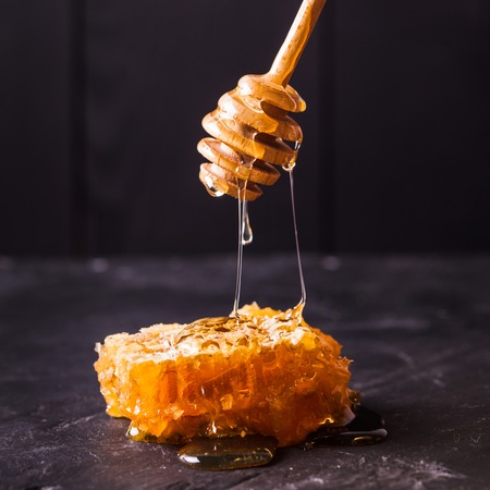 Honey drip and comb over black slate backgroundの写真素材