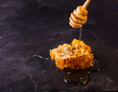Honey drip and comb over black slate backgroundの写真素材