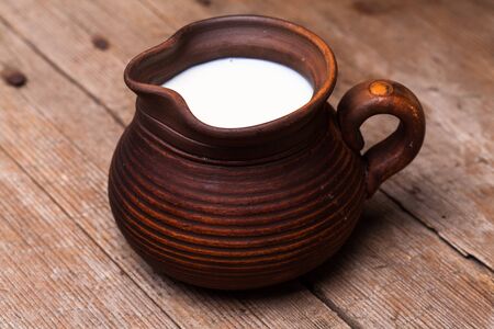 Milk in earthen jug on rustic woodtn tableの写真素材