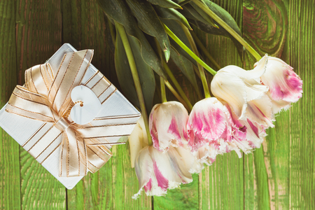 Pink tulips and gift box on a green wooden tableの写真素材