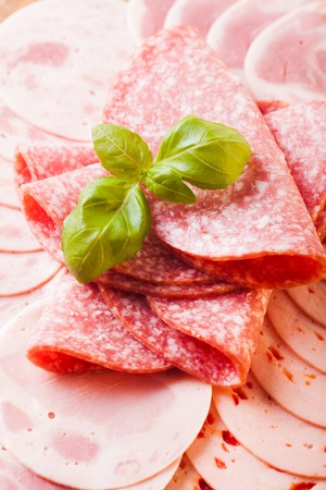 Cutting sausage and cold salami slices close upの写真素材