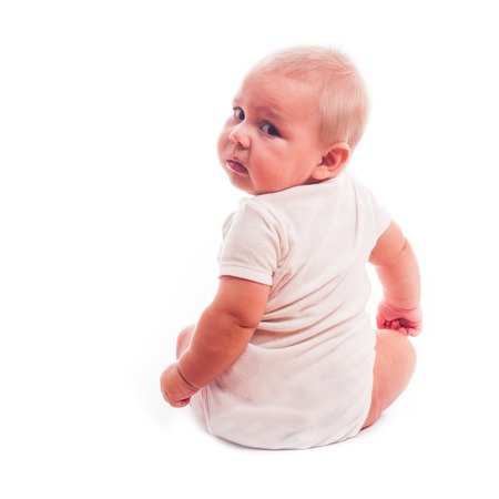 Portrait of a little boy that sitting and looking at camera over shoulder, isolated on white backgroundの写真素材