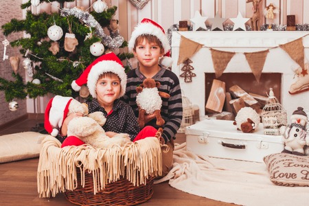 Two boys wearing Santa's hat with christmas decorations backgroundの写真素材
