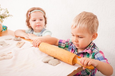 Little boy using a rolling pin that to roll modelling clayの写真素材