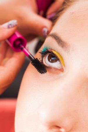Hand woman applying mascara on the eyelashes, close-up