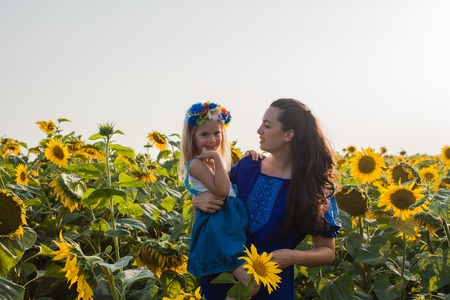 Mom and daughter among sunflowersの写真素材