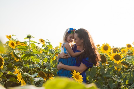 Mom and daughter among sunflowersの写真素材