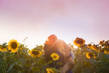 Mom and daughter among sunflowersの写真素材
