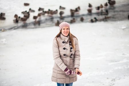 Girl feeding ducks in winterの写真素材