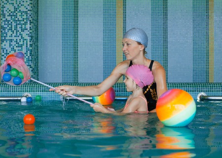 Girl and mother playing in the poolの写真素材