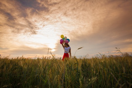 Girl with balloons in wheat fieldの写真素材