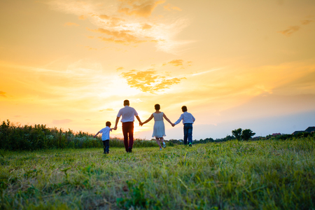 Happy family on the background of the sunsetの写真素材