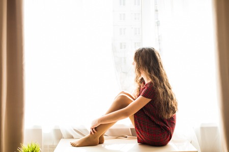 Cute teenager girl sitting near windowの写真素材