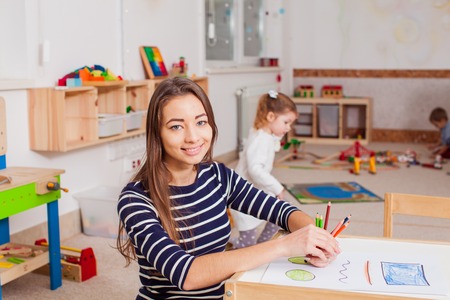 Smiling young preschool teacher in a kindergartenの写真素材