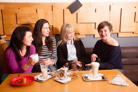 Girlfriends discussing the latest news during the informal meeting in cafeの写真素材