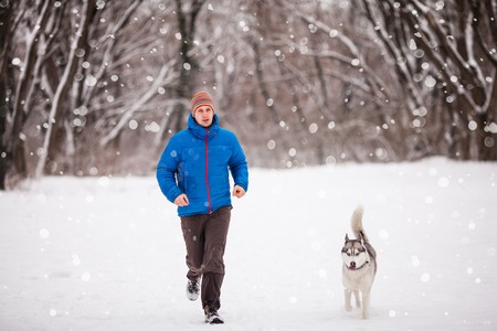 Man with husky dog are sunning in the cold winter morningの写真素材