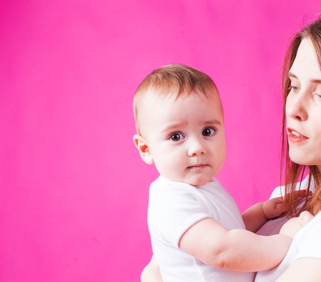 Infant baby looking at the camera, pink backgroundの写真素材