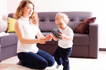 Young mother gives shoes to her small sonの写真素材