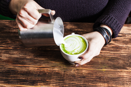 Process of pouring milk in matcha tea cupの写真素材