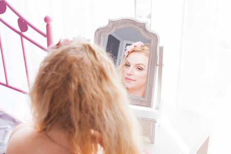 Charming woman looking in the mirror in her bedroomの写真素材