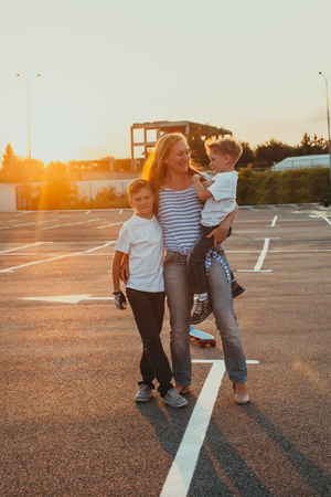 Young mother with her sons at the sunsetの写真素材
