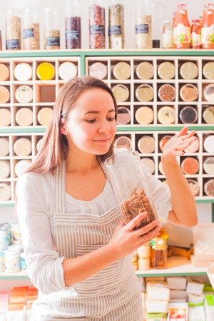 Woman smells the aroma of cinnamon in the glass jar