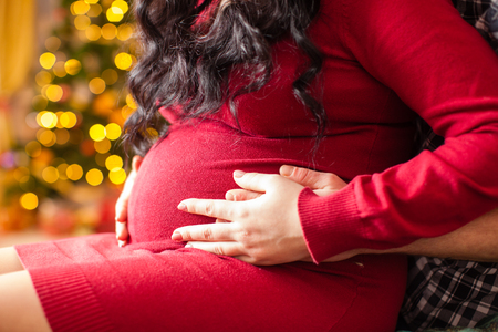 Young pregnant woman and happy father on the Christmas eveningの写真素材