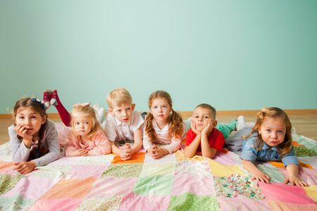Group of six kids laying on the floor at homeの写真素材