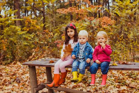 Three kids sitting on the bench and playingの写真素材