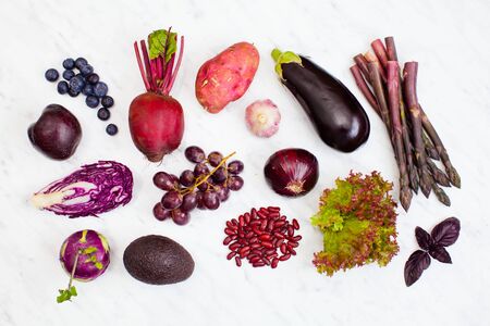 Raw purple vegetables and fruits over white marble background. Top view, flat lay.の写真素材