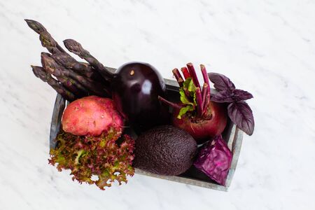 Top view of fresh vegetables in a wooden box on a white marble backgroundの写真素材